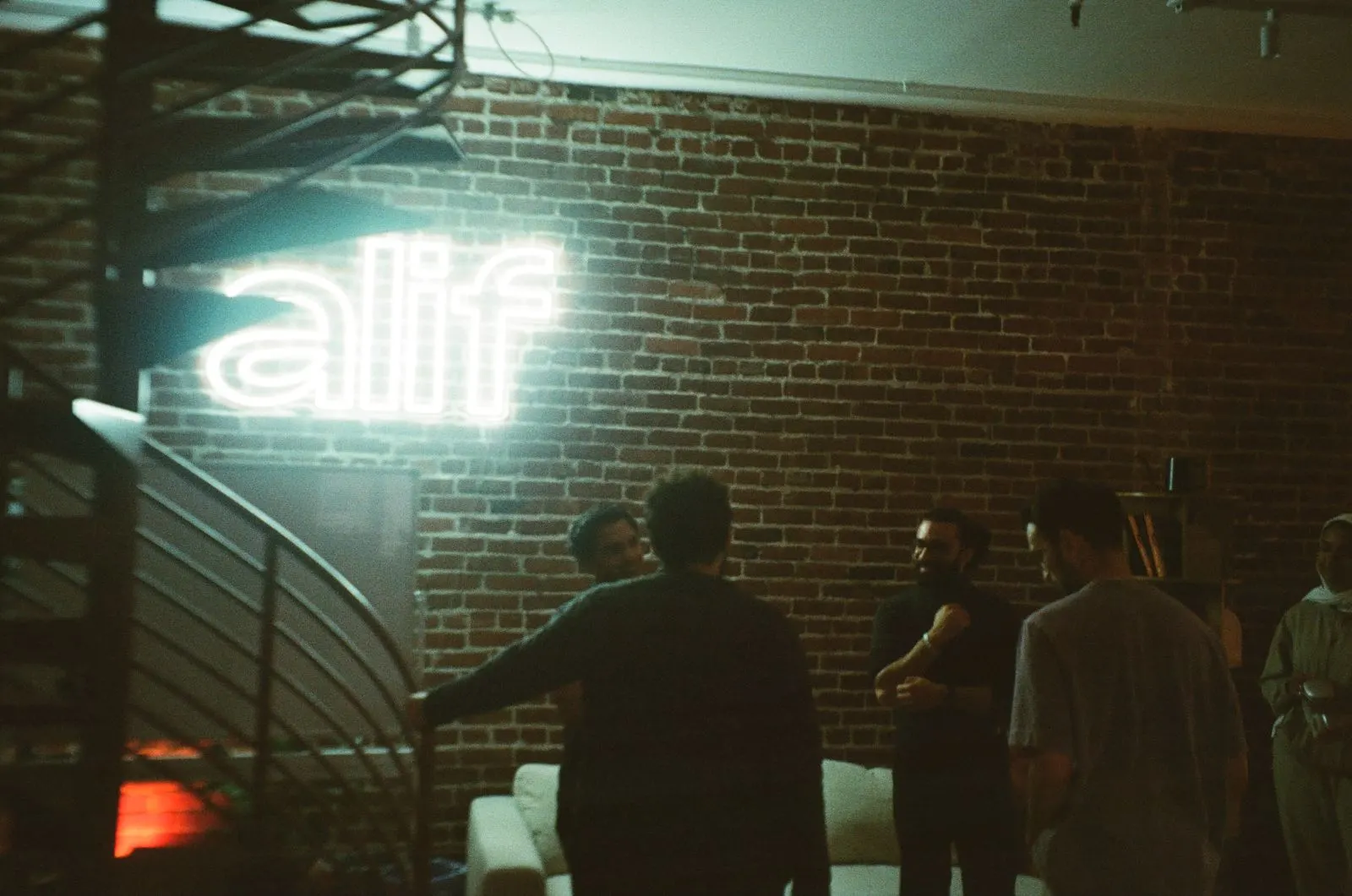 Builders gathering beneath the Alif sign