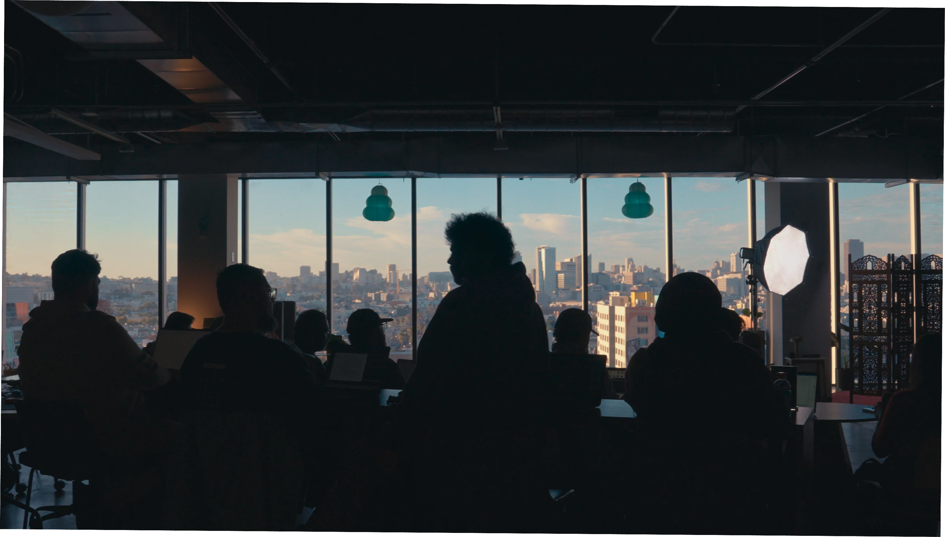 People gathered in a studio overlooking the city at sunset